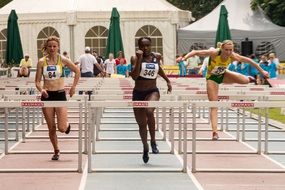 hurdling, young girls running and jumping over an obstacles