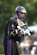 lacrosse player in black helmet and uniform at stadium