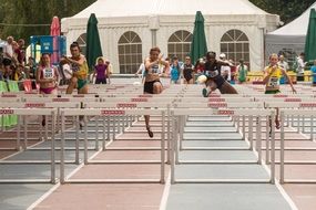 athletes running and jumping over obstacles on the track