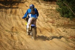 Motorcycle racer in dust on a race track on a sunny day