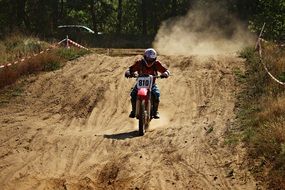 distant view of fast motorcycle racer on a dusty road