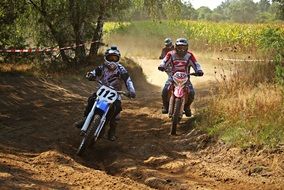Motorcyclists in the dust on a race track on a sunny day