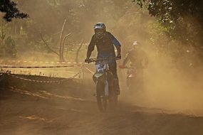 Motorcyclist in the dust on a race track on a sunny day