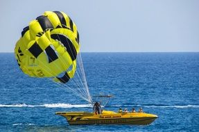 man with yellow parachute on boat in sea