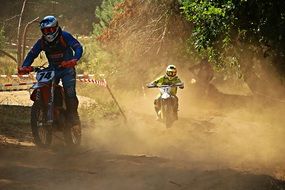 motorcycle racers in a dusty haze on the track