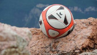 soccer ball on a rock near a lake