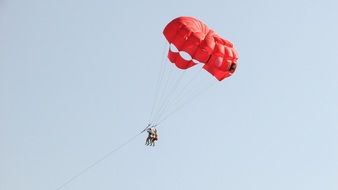 red parachute with two paragliders