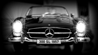 front view of a black 1950s Mercedes with bright headlights in a miniature