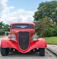 red hot rod car on a city street