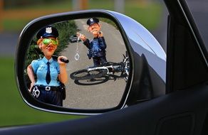 road accident with bicycle and policemen figures as reflection in the car mirror