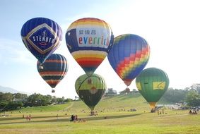 colorful hot air balloons above meadow, China, Taiwan