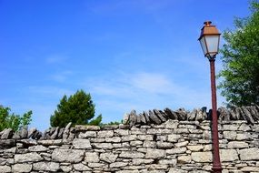 Street lamps near a stone wall