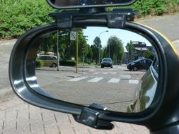 reflection of a road intersection in a side mirror of a car