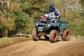 athlete on cross-country ATV among green plants