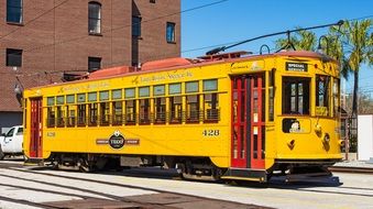 yellow retro tram near a brick building