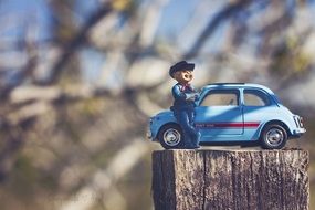 Man figure with the blue car on the wood on blurred background