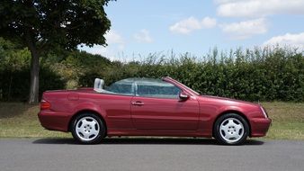 Red Mercedes Benz is standing on the road