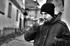 man with a cigarette on a city street in black and white image