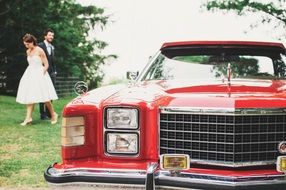 newlyweds near the red wedding limousine car