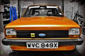 An orange retro car is standing in a garage