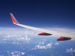 white-red wing of a airplane in the clouds