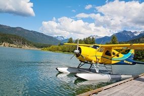 small yellow bi-plane on the water