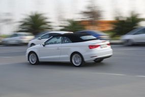 white convertible rides on the road at high speed