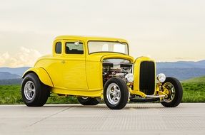 Yellow classic muscle car on the landscape with mountains on horizon