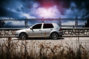 A gray Volkswagen stands near a golf course