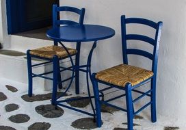 Blue chairs and a table stand near the wall