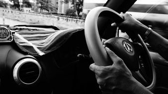 black and white photo of a man driving a car