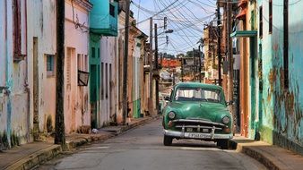 Green retro car on a beautiful and colorful city street in Cuba