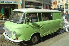 green retro car on a city street on a sunny day