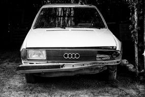 A black and white photo of a white Audi after an accident