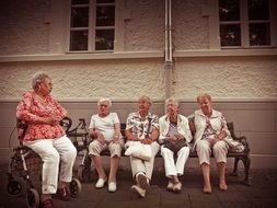 Pensioners rest on a bench near the house