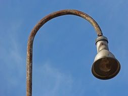 Rusty street lamp against the blue sky