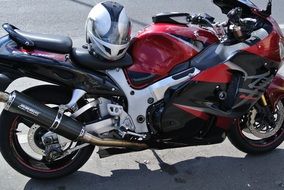 Shiny red and white motorcycle with helmet in the street