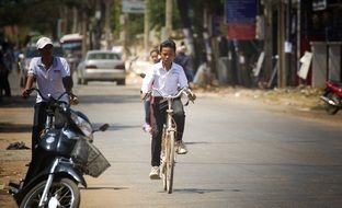 People are riding on the bikes on the road in Cambodia