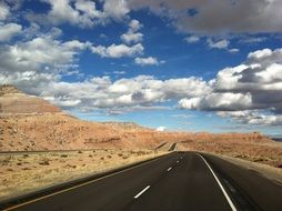 Landscape with the road under the blue sky with the white clouds