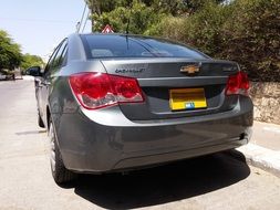 gray Chevrolet car stands on the side of the road on a sunny day