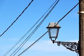 forged mount of a street lamp on an electric pole