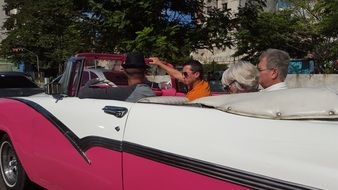 people in pink and white vintage convertible