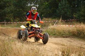 athlete on an ATV racing on a sandy road