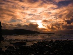 dramatic Sunset on rosky coast at stormy sea, Ireland
