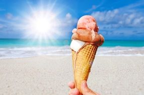 ice cream in man’s hand on a background of the sun over the water