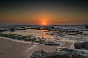 view from the beach to the sunrise on the ocean horizon
