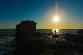 silhouette of a man on a rocky coast in Portland, England