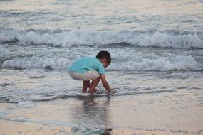 child boy plays in water on Beach at Surf line