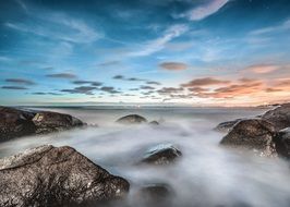 surf on rocks at ocean, long exposure