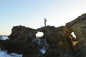 Man is climbing on the rocks near the ocean